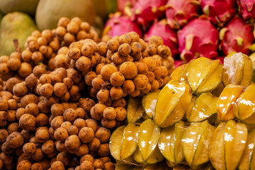 A pile of Asian fruits on the shelves, including bananas, mangoes and starfruit