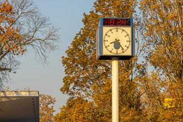 Dual Time Digital and Analogue Public Clock at Sunny Autumn Morning