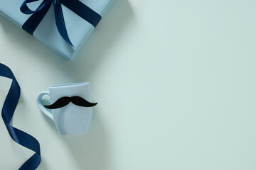 Plakat Happy Fathers Day. Creative greeting card with blue cup of coffee, tie and gift box on light blue background. Men's accessories set. Top view. Copy space.