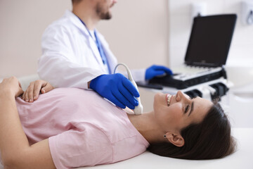 Sonographer conducting ultrasound examination of woman's thyroid gland in clinic, closeup