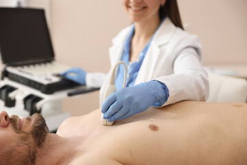 Fototapeta premium Sonographer conducting ultrasound examination of man's heart in clinic, closeup