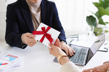 Money bonus. Employee receiving envelope with bow from boss in office, closeup