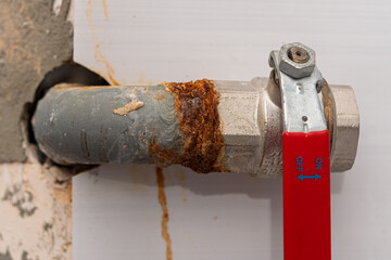 Rusty metal pipe with ball valve and corrosion stains highlights need for urgent plumbing repair...