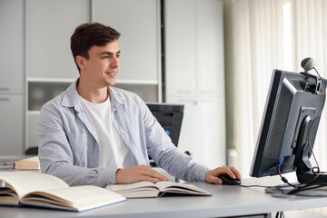 Obraz premium Man working on computer at desk in public library