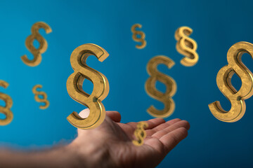 Abstract image of golden paragraph symbols falling onto an open hand, symbolizing legal concepts.