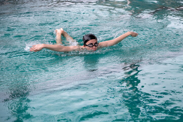 Asian male swimmer swimming butterfly stroke in pool