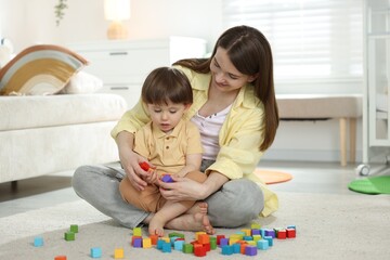 Naklejka premium Mother and son playing with colorful cubes at home