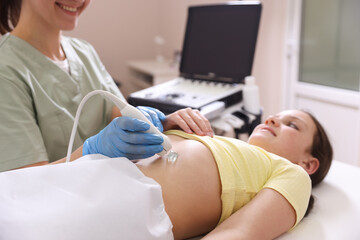 Sonographer conducting girl's abdominal ultrasound examination in clinic, closeup