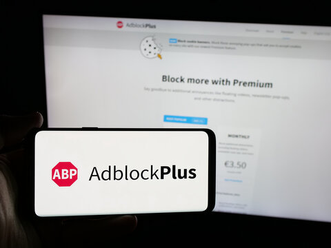 Stuttgart, Germany - 05-29-2025: Person holding smartphone with logo of ad blocking company Adblock Plus (eyeo GmbH) on screen in front of website. Focus on phone display.