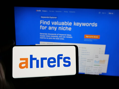 Stuttgart, Germany - 05-29-2025: Person holding smartphone with logo of SEO tools company Ahrefs Pte. Ltd. on screen in front of website. Focus on phone display.