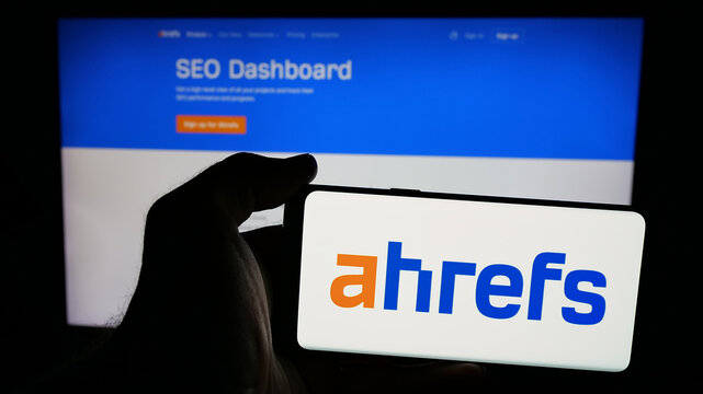Stuttgart, Germany - 05-29-2025: Person holding mobile phone with logo of SEO tools company Ahrefs Pte. Ltd. on screen in front of web page. Focus on phone display.