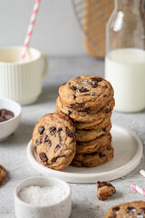 Stack of homemade American brown butter chewy, fluffy and soft chocolate chip cookies on a plate with salt and milk. Biscuits for children. Selective focus.