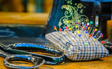 Crafting tools arranged on a wooden table with a vintage sewing machine in the backdrop during a sunny afternoon