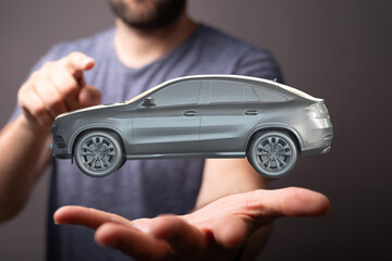 A man holds a digital rendering of a modern SUV, showcasing car sales or technology.