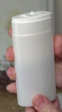 A woman's hand unscrews a natural SPF stick in a white tube. Minimalist white and beige background. Organic sun protection. Clean beauty skincare concept with eco-friendly packaging.
