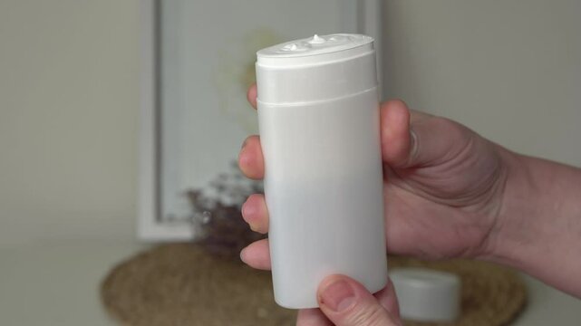 A woman's hand unscrews a natural SPF stick in a white tube. Minimalist white and beige background. Organic sun protection. Clean beauty skincare concept with eco-friendly packaging.