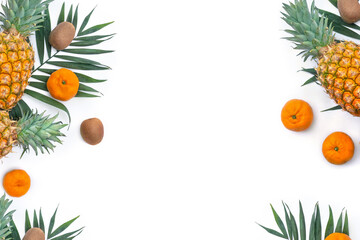 Tropical fruits, pineapple, tangerine, kiwi and palm leaves on a white background with copy space for text. Top view, flat lay