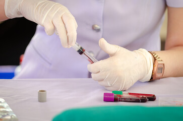 Nurse wearing white medical gloves is drawing blood from patient's arm for examination or PRP procedure. Concept of laboratory research, medicine, analysis.