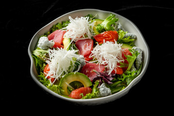Fresh salad with mixed greens, avocado slices, grapefruit segments, tuna, salmon, and shredded...