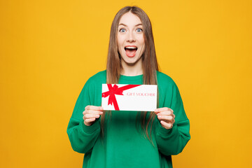 Young surprised shocked woman wears green sweatshirt casual clothes hold gift certificate coupon...