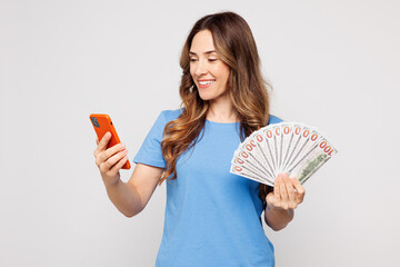 Young Caucasian woman wear blue t-shirt casual clothes hold in hand fan of cash money in dollar...