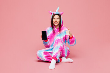 Full body young woman wear domestic costume with hoody and animal ears sit hold use blank screen mobile cell phone show thumb up isolated on plain pink background studio portrait. Lifestyle concept.