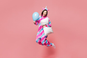 Full body young woman she wearing domestic costume with hoody and animal ears jump high with blue balloon and pillow isolated on plain pastel light pink background studio portrait. Lifestyle concept.