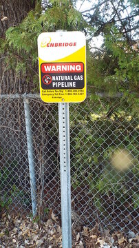 Ottawa, ON, Canada-June 03,2025: A yellow and white warning sign for an "Enbridge Natural Gas Pipeline" on St. Laurent Blvd.
