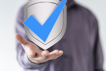 Hand holding a shield with a check mark, symbolizing security, safety, and data protection.