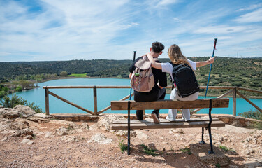 couple sitting on bench embracing and enjoying lake view after hike
