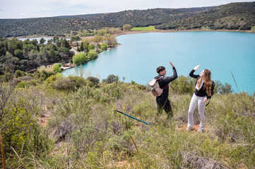 Teen girl and boy celebrating with a high five after completing a challenging hike, standing victorious on a hilltop with a turquoise lagoon in the background