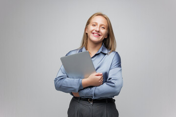 Fototapeta premium Confident Young Professional Smiles While Holding a Laptop in a Modern Office Setting During a Bright and Productive Workday