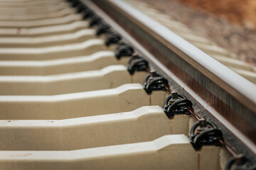 Detailed view of rusted steel railway tracks mounted on white concrete sleepers, captured at a...