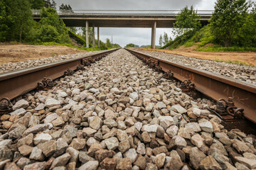 Symmetrical view of railway tracks stretching into the distance and passing beneath a concrete...