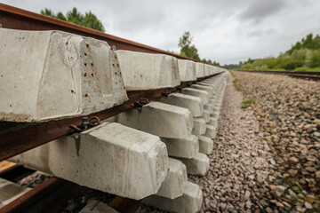 Neatly stacked concrete and steel railway track sections are positioned along an active railway...