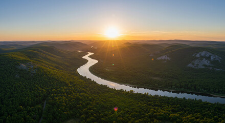A wide aerial view of a winding river cutting through green forest.
