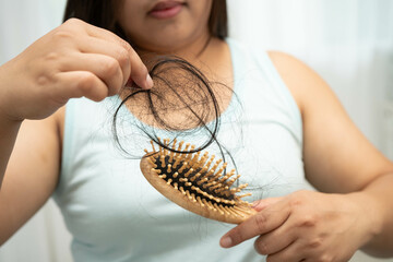 Asian woman have problem with long hair loss attach to comb brush.
