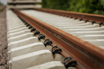 Detailed view of rusted steel railway tracks mounted on white concrete sleepers, captured at a...