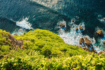 Ocean with waves crashing on rocks stones, view from high rocky coastline