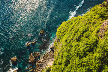 Ocean with waves crashing on stones, view from cliff coastline