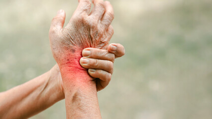 Close up of senior hand gripping inflamed wrist in pain with red highlighted area indicating joint...