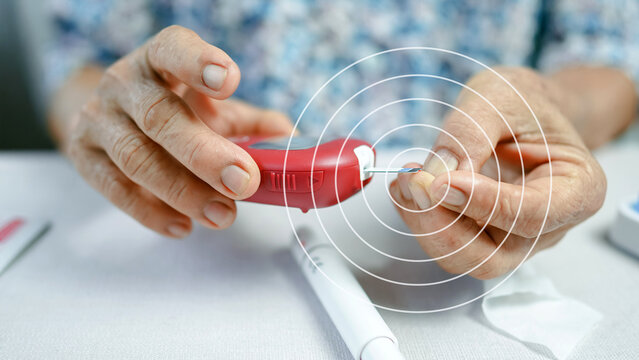 Close-up of elderly woman using red glucometer to check blood sugar after finger prick demonstrating daily diabetes management at home
