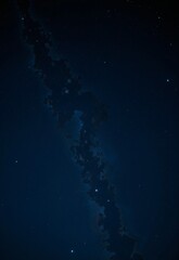 A mesmerizing night sky filled with countless stars and a dark, mysterious cloud formation stretching across the horizon
