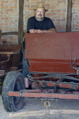 Farmer standing in barn near old vehicles
