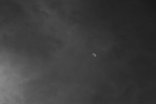 Moon shines through black and white abstract clouds