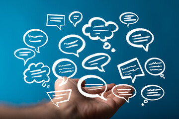 Image of hand holding multiple speech bubbles, ideal for communication, teamwork, and social media...