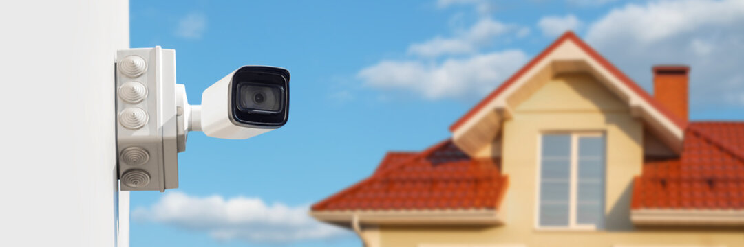 Long banner, Home Security Camera on Wall with House and Blue Sky Background.