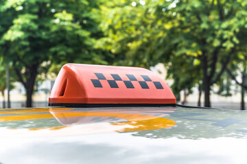 Red Taxi Sign on Car Roof with Green Trees Background
