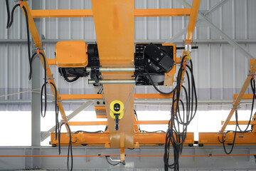 Overhead crane in factory or warehouse building. Industrial machine or lifting equipment with hoist, hook and wire rope move on beam structure for process in storage, manufacturing and production.