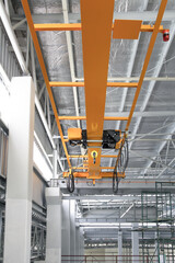 Overhead crane inside factory or warehouse building. Industrial machine or lifting equipment consist of hoist, hook and wire rope move on beam girder structure for manufacturing production plant.